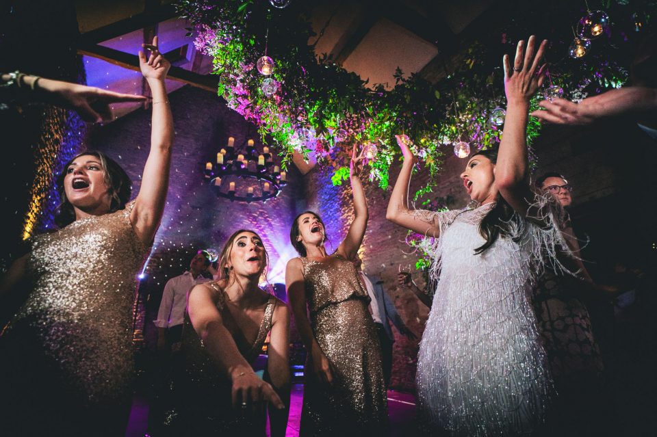 Bride and bridesmaids dancing at a Stone Barn wedding in The Cotswolds