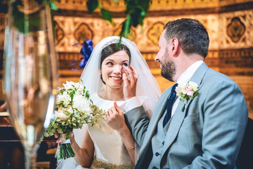 Groom wipes a tear from the bride at a wedding at St.Stephen's Rosslyn Hill in London