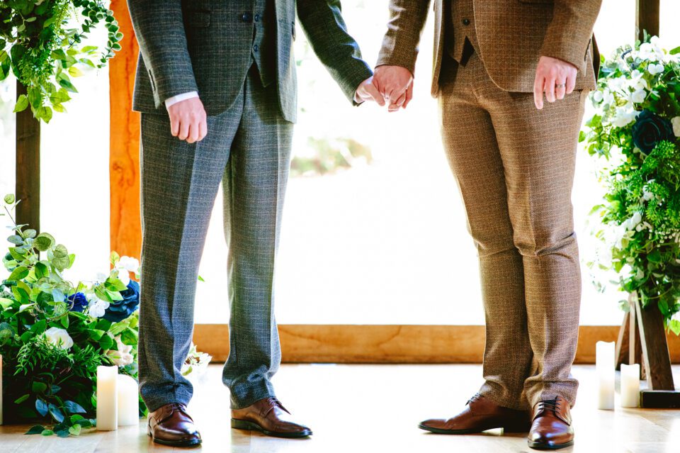 Grooms holding hands during the ceremony
