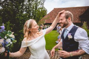 Bride brushing confetti off the groom at a wedding at The Priory Little Wymondley in Hertfordshire.