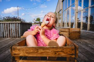 A young girl licking an ice cream in a crate