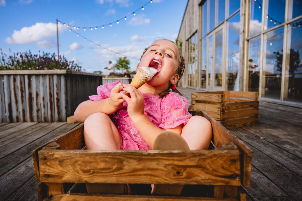 A young girl licking an ice cream in a crate
